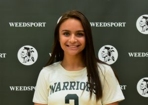 Aubrey Ouderkirk poses for a picture against a background.