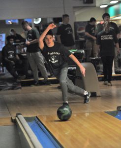 A student on the bowling team throws the ball down the lane.