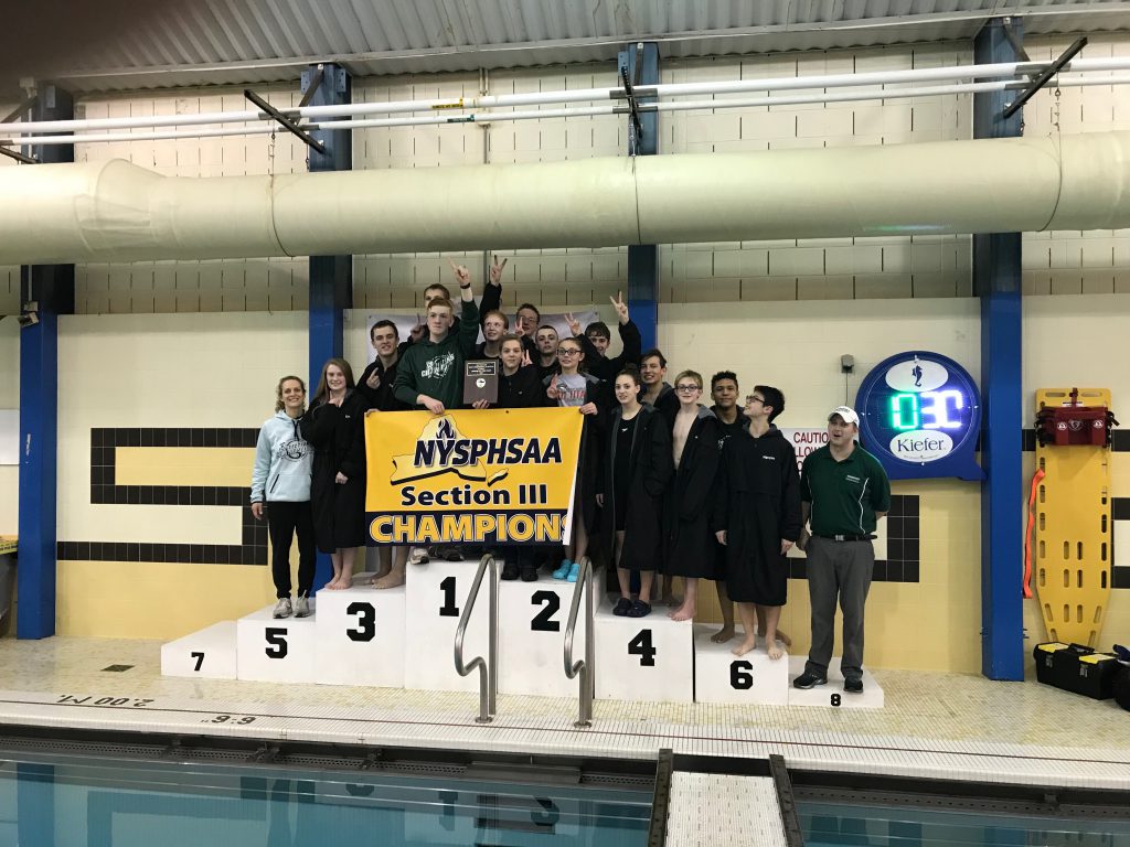 A picture of the swimming and diving team with the sectional championship banner