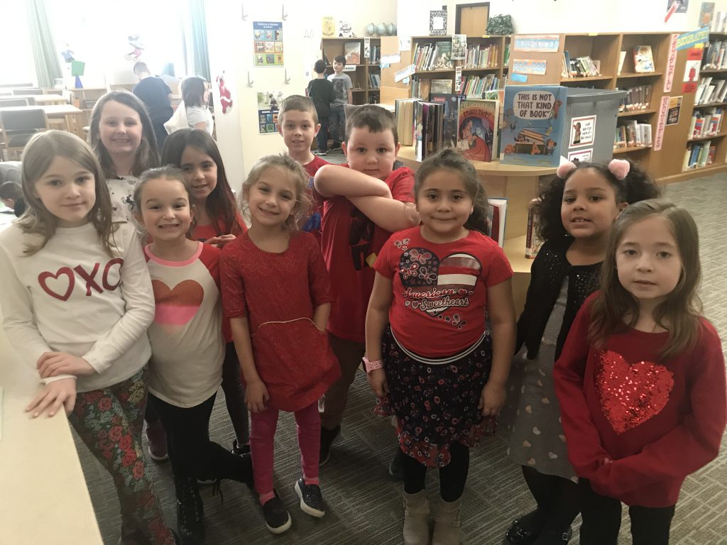 Elementary students pose for the camera wearing red 