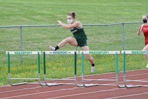 Mariah Quigley leaps over a hurdle in a track meet