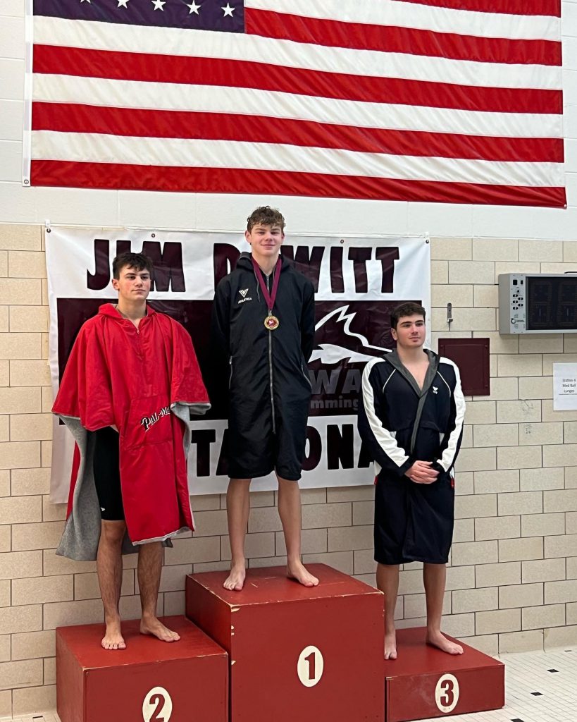 Nolan Carner stands on the podium after coming in first place during the 100 yard freestyle.