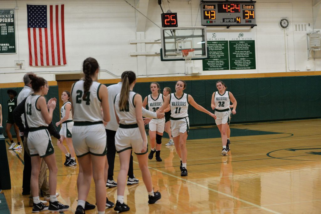 Members of the varsity girls basketball team walk to the side of the court.