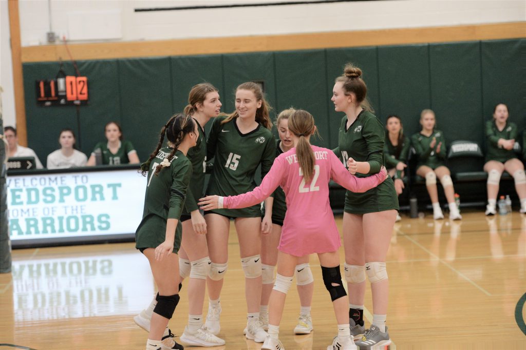 The girls varsity volleyball team celebrates after winning a point.
