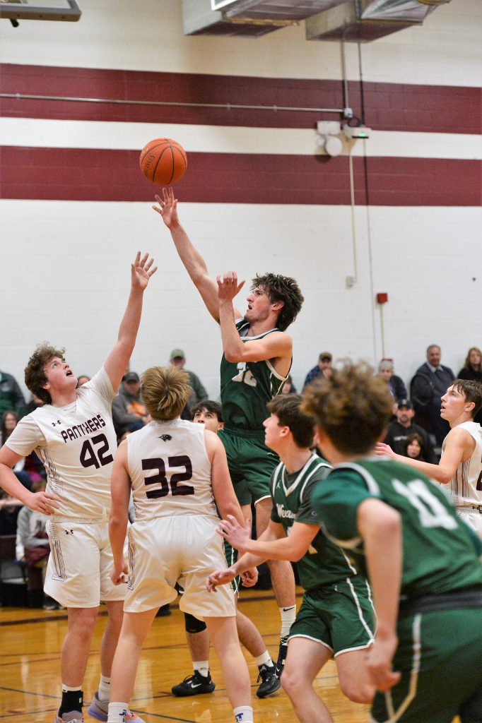 A varsity basketball player jumps up to take a shot during a game.