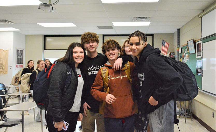 Jr.-Sr. High School students smile for a photo inside of a classroom.