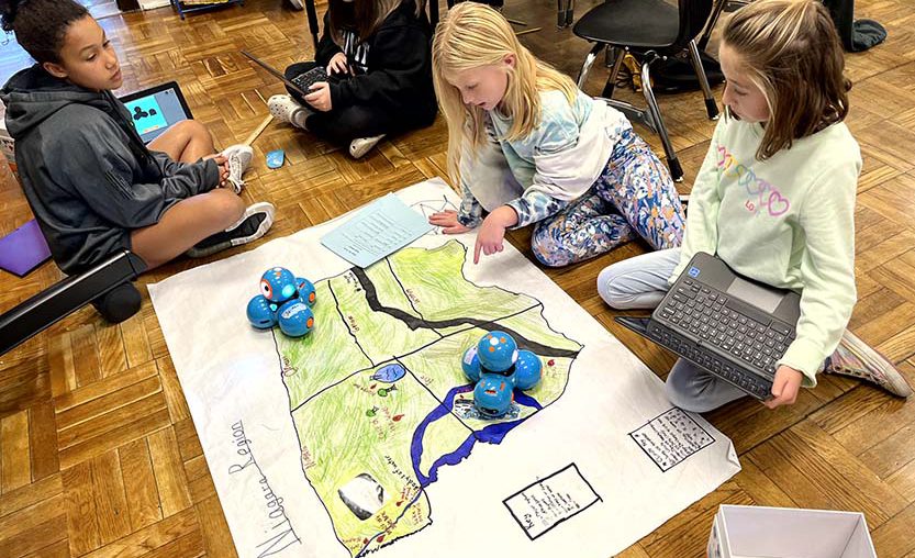 Elementary students work on coding a robot.